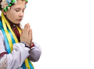 A little girl in national Ukrainian clothes with tearful eyes folded her hands in front of her and prays for an end to the war in Ukraine.