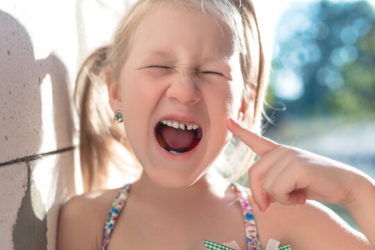 Little girl points the finger at a wobbly baby tooth