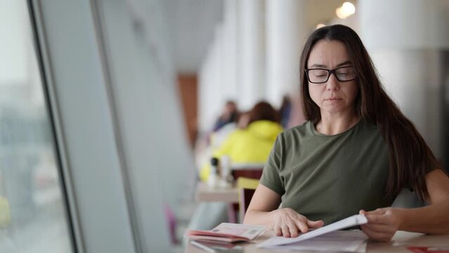 woman is checking passport, papers and visa form before flight and travelling in airport cafe