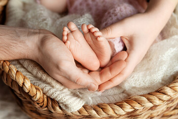 Baby feet in parents hands. Tiny Newborn Baby's feet on ffamily hands closeup. Mom, dad and they child. Happy Family concept. Beautiful conceptual image of Parenthood