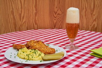 Chicken escalope or schnitzel served on white porcelain plate with sweet and sour pickled cucumbers and mashed potatoes as a side dish and glass of czech pilsner beer. Traditional and tasty lunch.