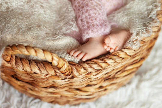 Tiny foot of newborn baby. Soft newborn baby feet against a beige  blanket. Baby feet with toes curled up