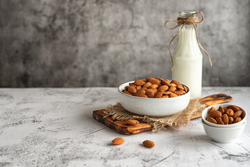 Obraz na płótnie Canvas Almond milk in a glass bottle and almonds on a gray marble table. Horizontal photo. Copy space. Top view.