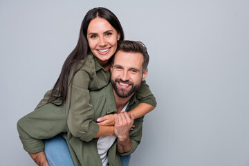 Portrait of attractive cheerful couple friends hugging having fun piggy backing weekend isolated over grey pastel color background