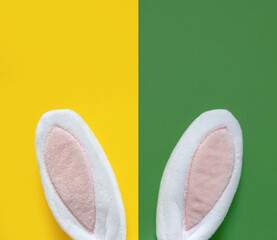Happy Easter. Simple Modern Print with Bunny Ears. Cute Easter Composition with White-Pink Rabbit Ears on a Geometric Yellow-Green Background ideal for Card, Poster, Greetings. 