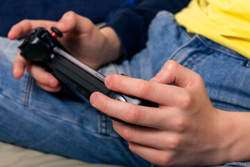 Teenager playing on his phone with console. 