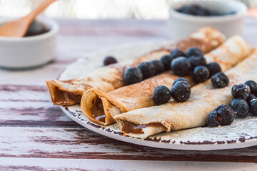 Delicious plate with homemade pancakes or crepes filled with dulce de leche and blueberries and...