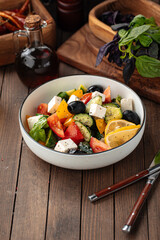 Bowl of fresh greek salad on wooden background