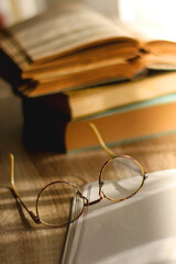 Open book, mechanical pencil, reading glasses, mobile phone and strack of books on the desk. Studying concept. Selective focus.