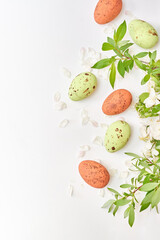 Obraz na płótnie Canvas Branches with green leaves and easter eggs on a white background. Happy easter flat lay concept