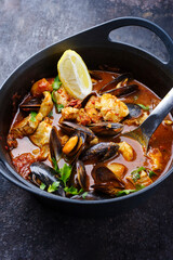 Modernes traditionelles spanisches Meeresfrüchte-Zarzuela de Pescado mit Fisch, Riesengarnelen und Miesmuscheln in roter Chilisauce als Draufsicht im Design Topf mit Textfreiraum