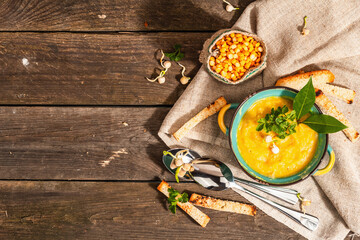 Pea cream soup in a bowl on vintage wooden background. Dry legumes, toast, croutons and greens