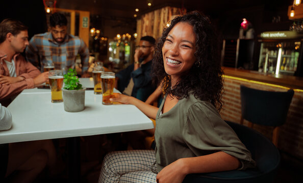 African american female laughing while enjoying drinks with friends 