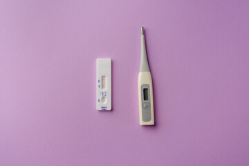 Express test for covid-19 with a positive result and a thermometer on a purple background. Coronavirus self-test kit