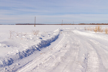 Fototapeta na wymiar a cleared winter road through a field