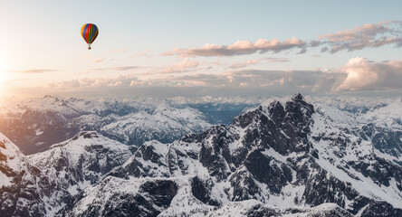 Dramatic Mountain Landscape covered in clouds and Hot Air Balloon Flying.