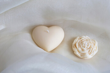 Handmade candle heart and flower on the gentle textile background. Natural eco-friendly home decor. Spa composition.