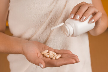 woman pouring pills into her palm from a bottle close-up