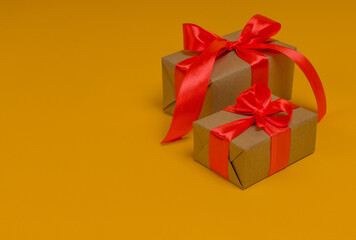 holidays concept, two gift boxes with a red bow on a yellow background, copy space