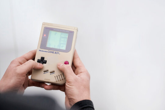 Madrid, Spain; 04-04-2022: Man holding in his hands a classic video game Nintendo Game Boy while playing the popular game Tetris