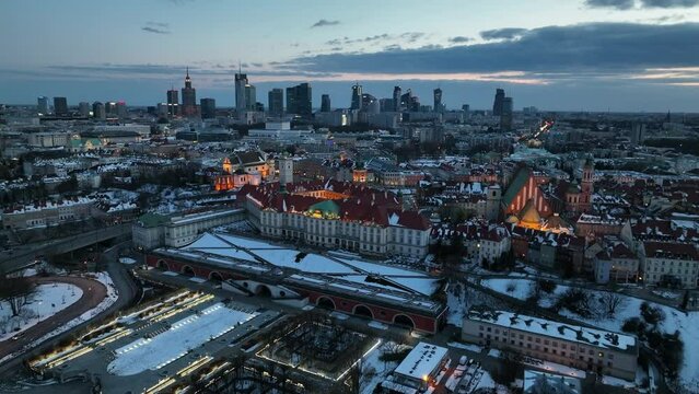 Widok na zamek kr&oacute;lewki i stare miasto w Warszawie z drona, w tle wieżowce, zaśnieżone dachy, zach&oacute;d słońca