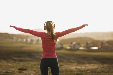 Woman Runner Is Listening To Music And Stretching Before Training Outdoors