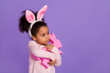 Portrait of attractive trendy pre-teen girl hugging bunny toy shop store copy space isolated over bright purple violet color background