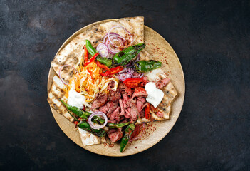Traditionelles griechisches Gyros vom Rindfleisch mit Karottensalat, Joghurt und Fladenbrot serviert als Draufsicht auf einer rustikalen Holz Board mit Textfreiraum