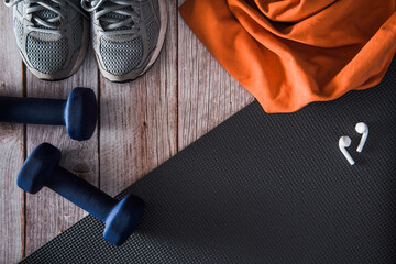 Fitness dumbbells, sneakers, and headphones on mat. Gym accessories. Copy space. Selective focus.