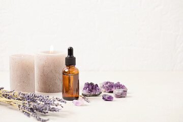 Glass bottle of Lavender essential oil with lavender flowers and candles and amethyst crystals. Meditation, zen, aromatherapy,spa massage concept - obrazy, fototapety, plakaty