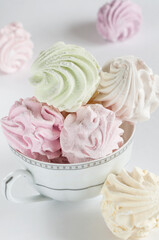 Marshmallows of different colors, close-up in a tea mug on a gray background. Selective focus, daylight