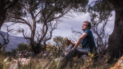 Naklejka na ściany i meble Young Man hiking in the Hills of Sicily in Spring Italy in Europe, relaxing on a meadow