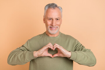 Photo of mature handsome man show fingers heart shape cupid romance isolated over beige color...