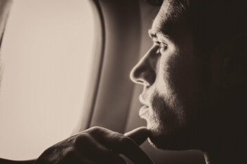 Young handsome man against plane window sitting