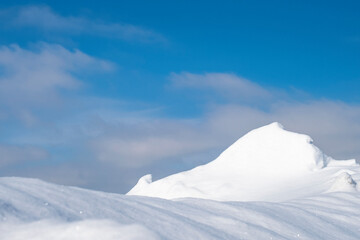 Fototapeta na wymiar Snowy mountain peak, blue sky with white clouds.
