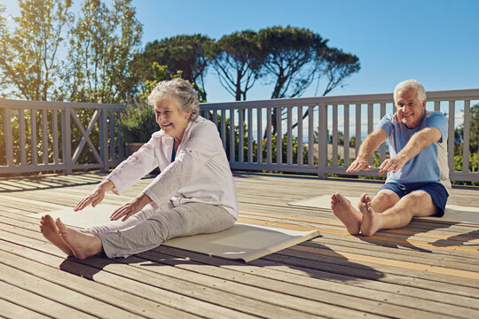 Keeping Lithe And Limber. Shot Of A Senior Couple Doing Yoga Together On Their Patio Outside.