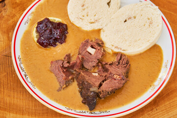 Top view on the traditional old czech slowly cooked beef sirloin in creamy sauce with dumplings, slice of lemon and cranberry. Mainly served as a wedding lunch. Typical example of the Czech cuisine.