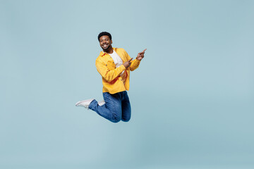 Full body young man of African American ethnicity 20s wear yellow shirt jump high point index...