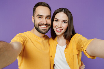 Obraz premium Close up young smiling couple two friends family man woman together in yellow casual clothes looking camera doing selfie shot pov on mobile phone isolated on plain violet background studio portrait.