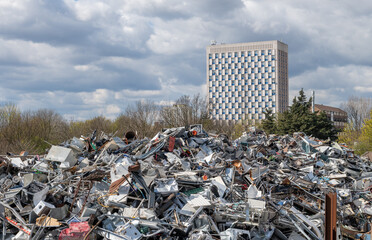 A huge pile of scrape metal products, parts by a high rise apartment block. - obrazy, fototapety, plakaty