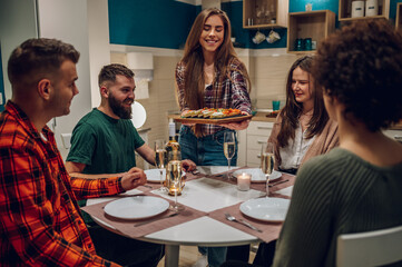Group of friends enjoying dinner while sitting at the kitchen table together