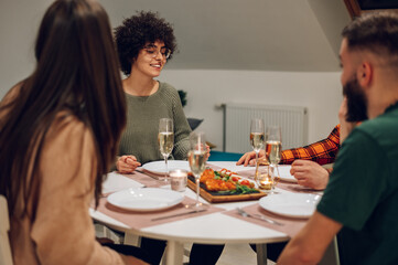 Group of friends enjoying dinner while sitting at the kitchen table together