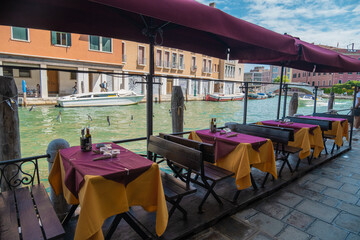 Naklejka premium VENICE, ITALY - August 27, 2021: View of empty restaurant tables due to the pandemic on the canals of Venice