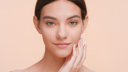 Close-up beauty portrait of young woman who gently lays her fingers on the jawline | Pure skin and skin care concept.