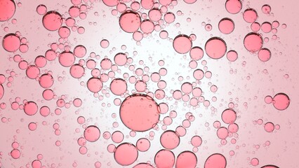 Pink different sized oil drops floating in transparent liquid on pale pink background | Background shot for skin care lotion with glycerin commercial