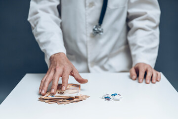hand of a doctor taking lot of bill next to bunch of pills