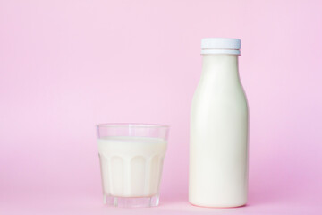 A bottle and a glass of white milk, highlighted on a pink background, close-up.