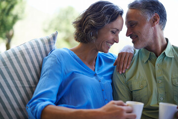 I live to make her laugh. A cropped shot of a happy mid adult couple drinking coffee together on their sofa.