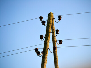 Electric pole with wires on a field in the countryside.