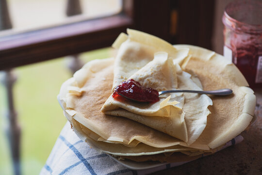 Thin crepes and strwberry jam served on a plate. Rustic style